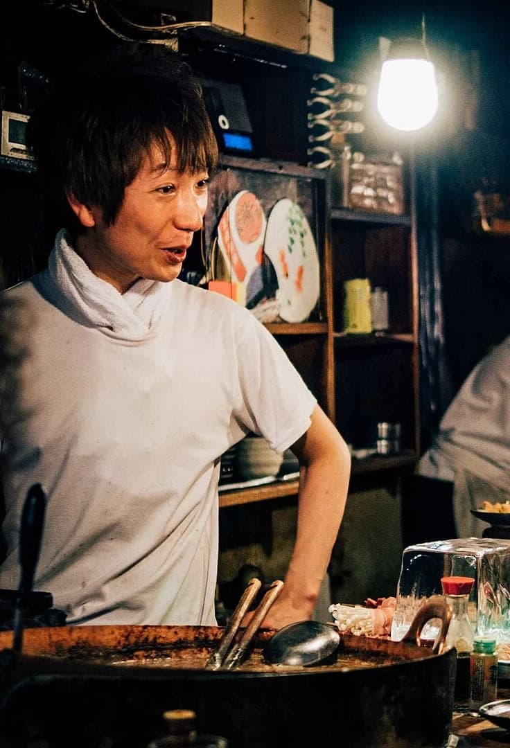 Cocinero, barra, platos y cliente en un pequeño izakaya de Tokio