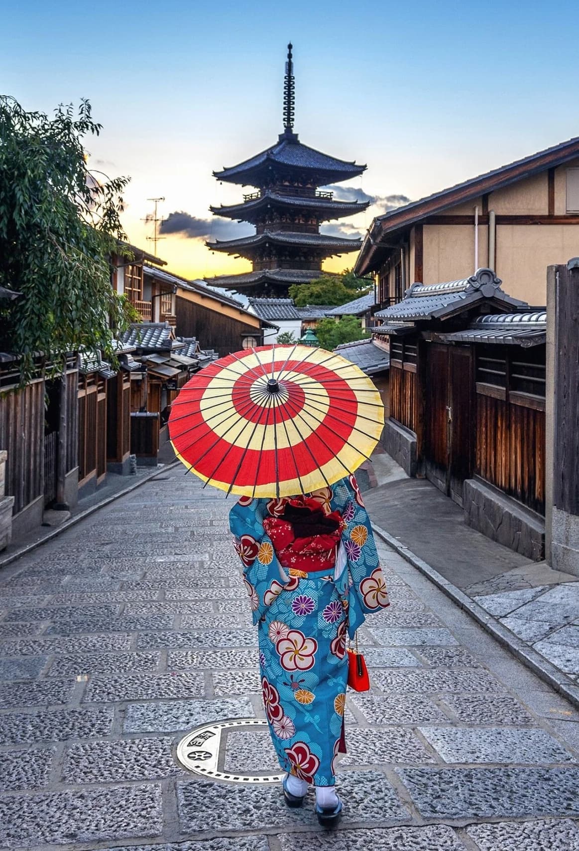 Mujer con kimono y parasol rojo frente a la pagoda de Yasaka en Kioto