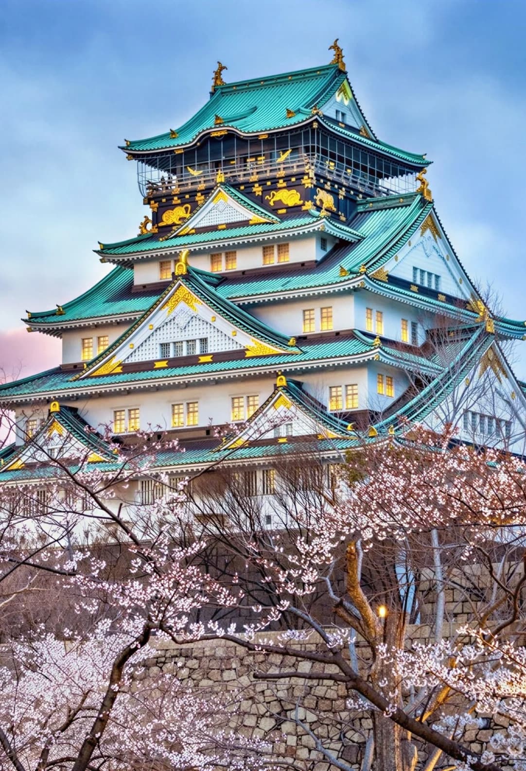 Castillo de Osaka rodeado de cerezos en flor al atardecer