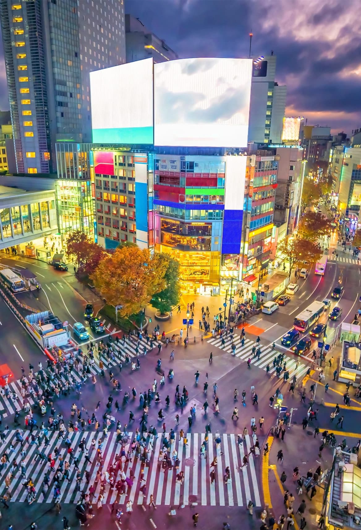 Multitud cruzando el famoso cruce de Shibuya entre pantallas luminosas de Tokio