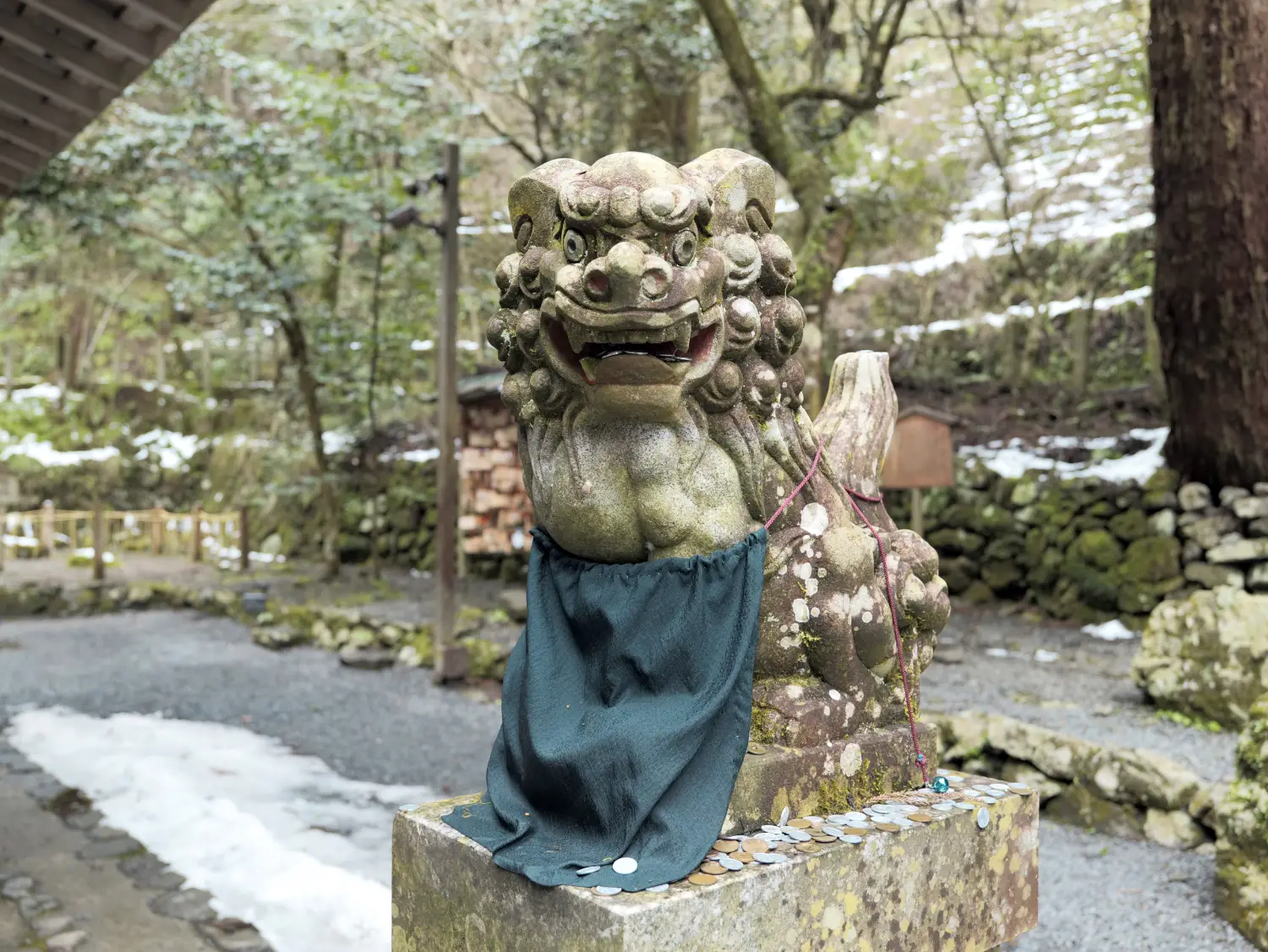 Uno de los perros guardianes de piedra del santuario de Kifune, con nieve alrededor