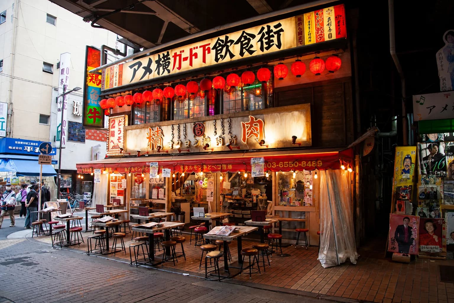 Un local de comida con farolillos rojos bajo las vías del tren en Ameya-Yokocho