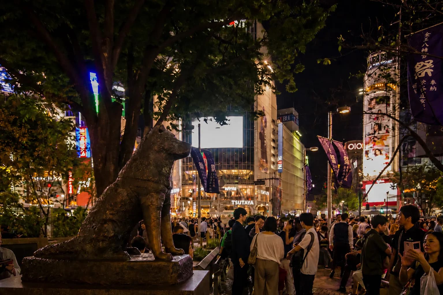 La estatua de bronce de Hachiko al anochecer, rodeada de gente