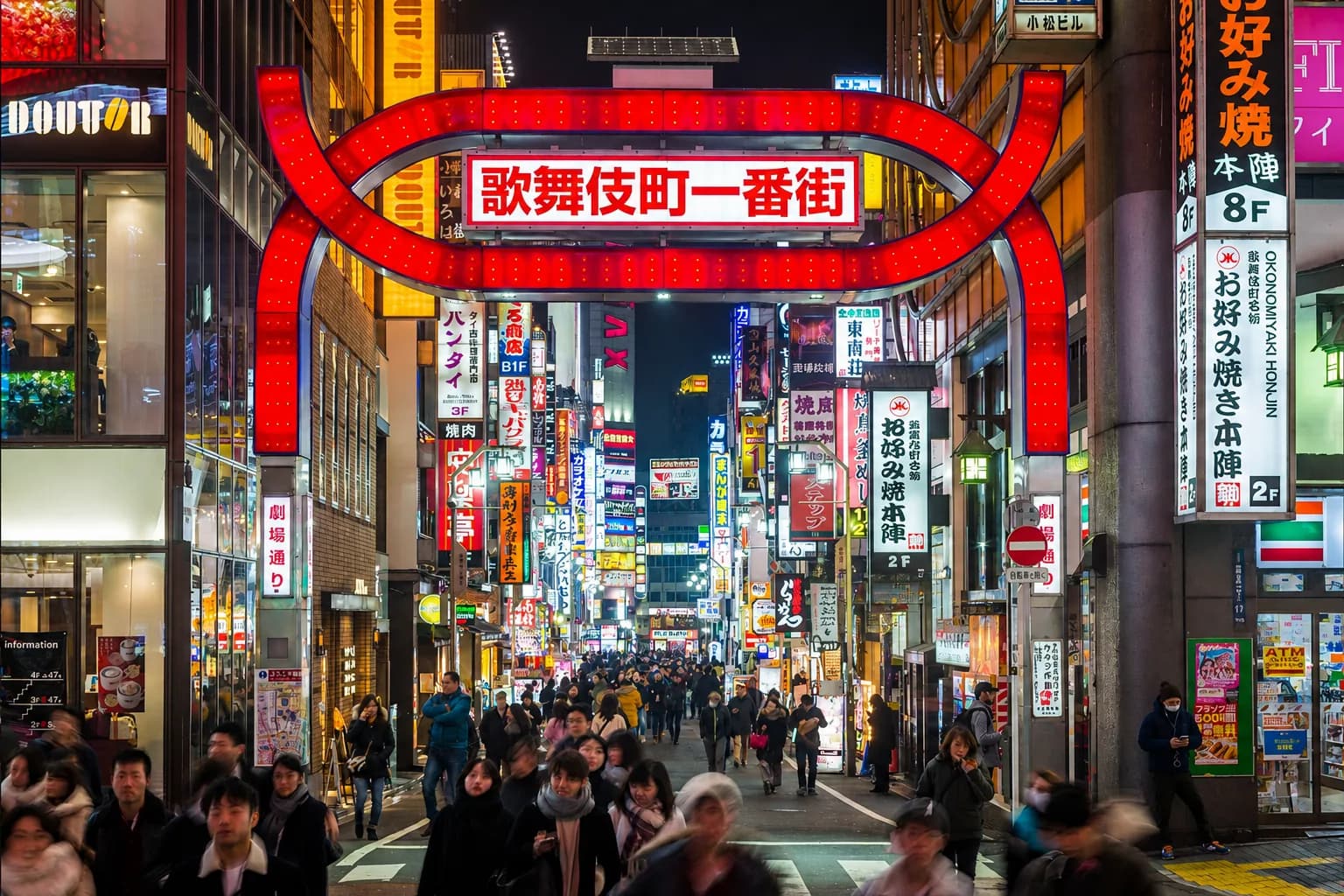 El arco rojo iluminado de Kabukicho Ichibangai, lleno de gente por la noche