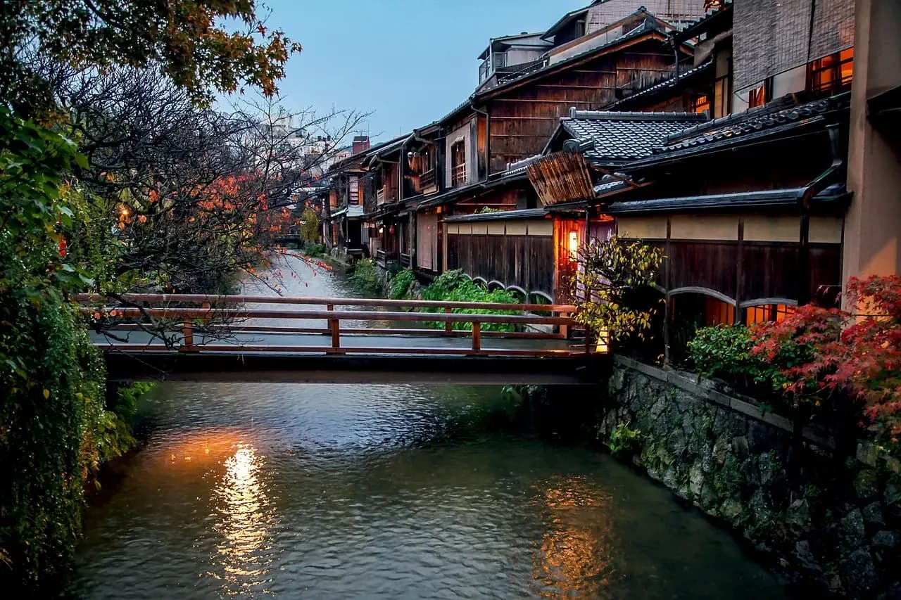 El canal de Gion Shirakawa al anochecer, con sauces, farolillos y un puente de piedra