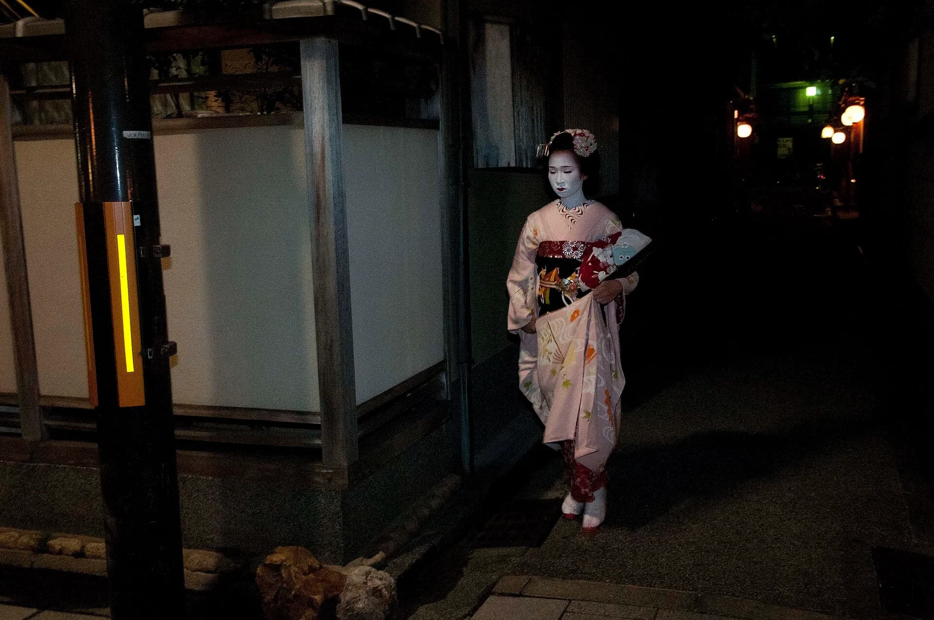 Una maiko con kimono y adornos en el pelo caminando por Gion