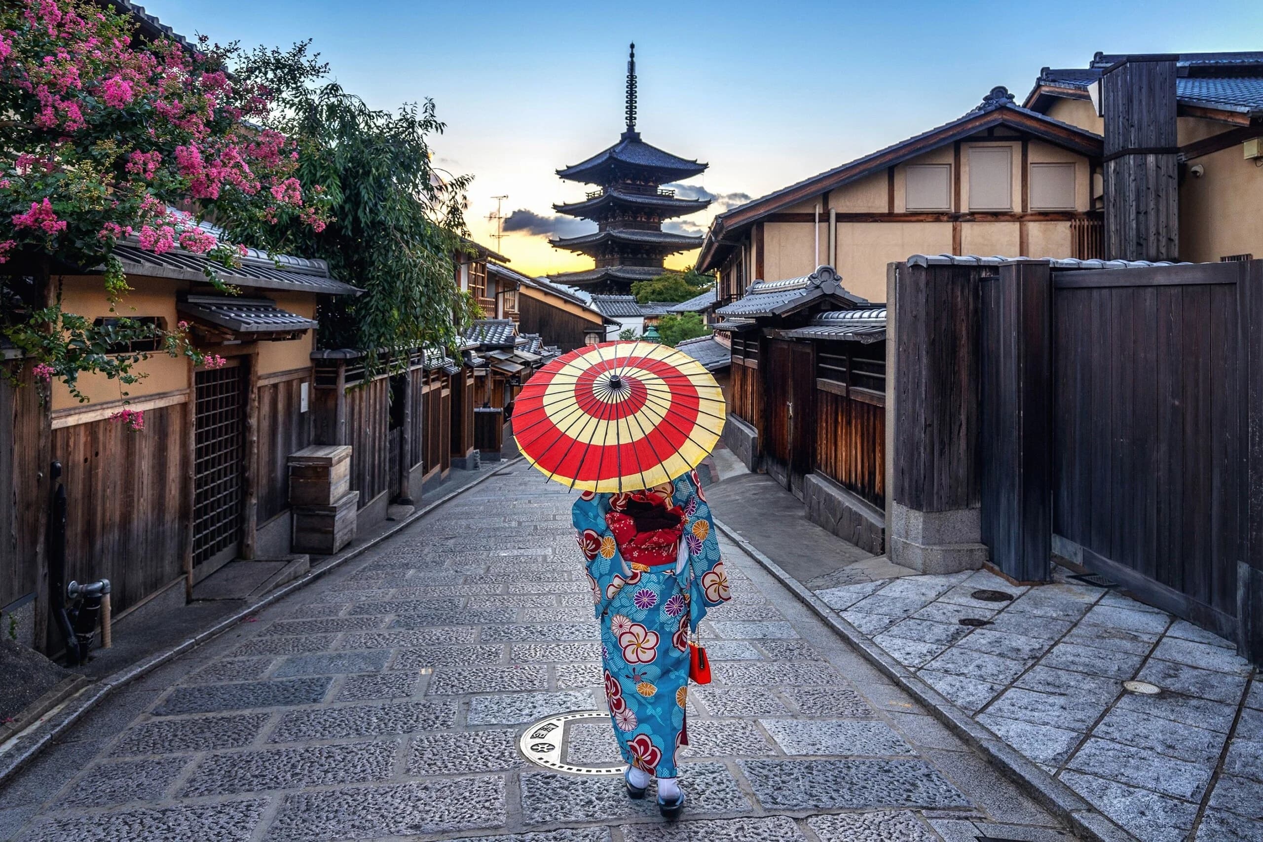 Mujer con kimono y parasol rojo frente a la pagoda de Yasaka en Kioto