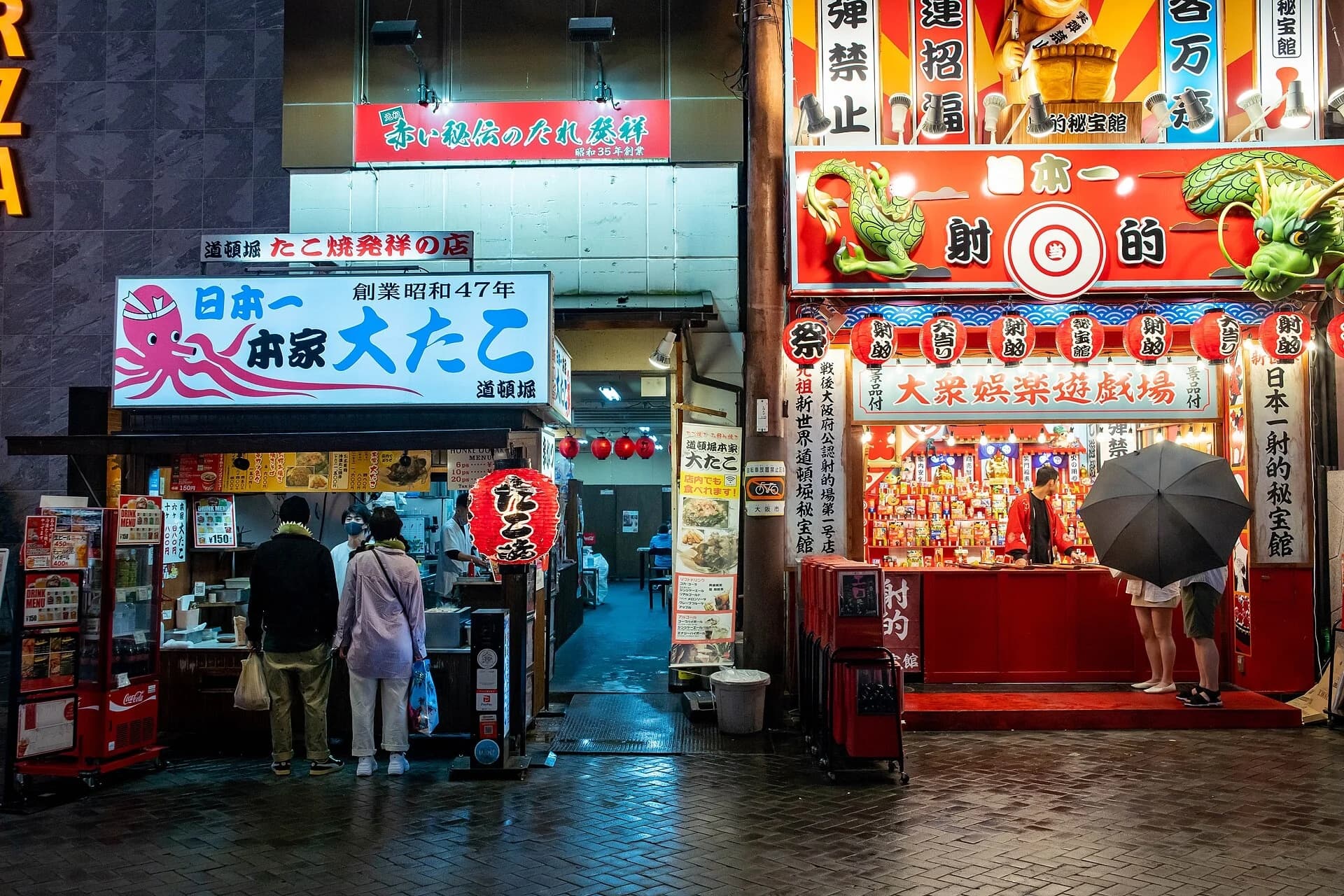 Clientes ante un puesto iluminado de takoyaki en Dotonbori durante la noche