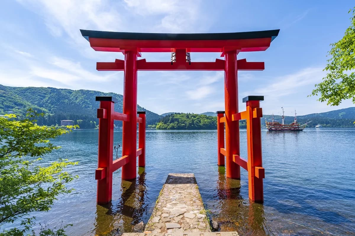 El torii rojo del santuario de Hakone plantado en el agua del lago Ashi