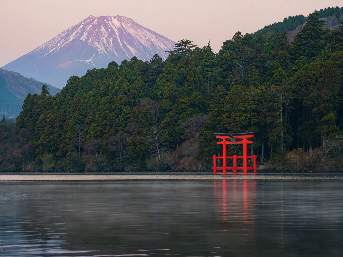 El monte Fuji nevado sobre el lago Ashi, con el torii rojo del santuario de Hakone en la orilla