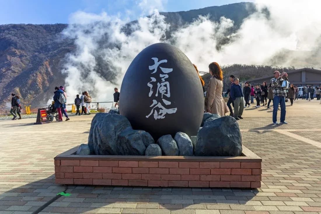 El monumento del huevo negro de Owakudani, con las fumarolas de azufre detrás