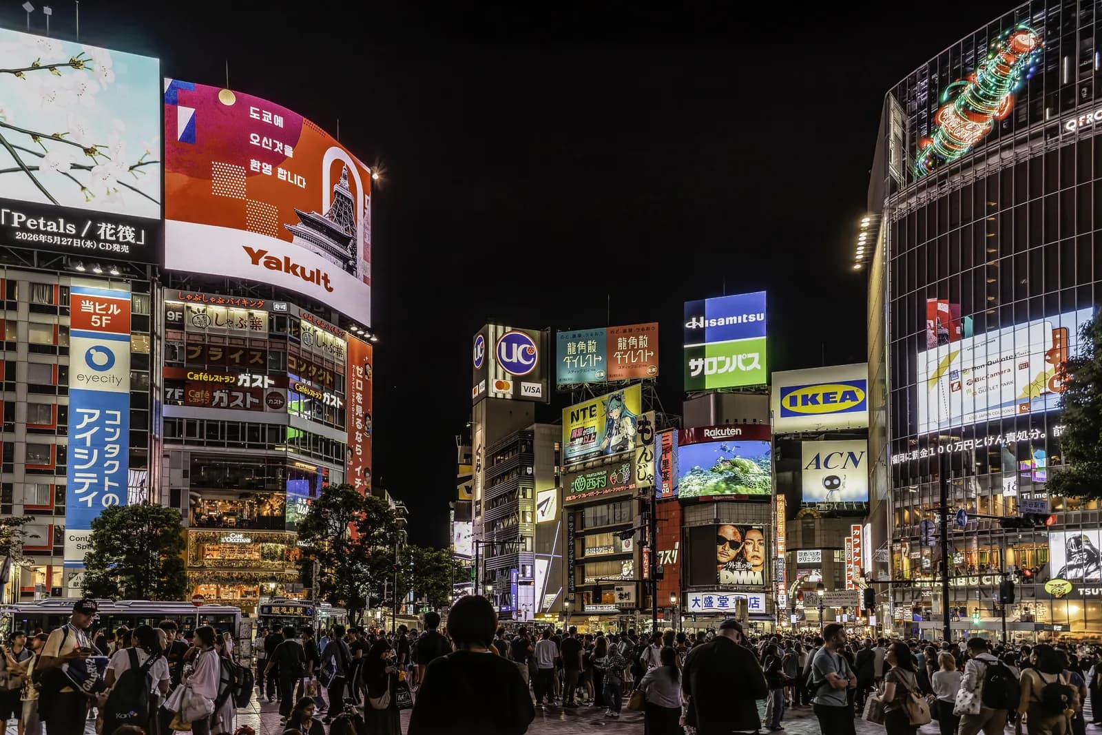 El cruce de Shibuya de noche, lleno de gente, con las pantallas gigantes encendidas
