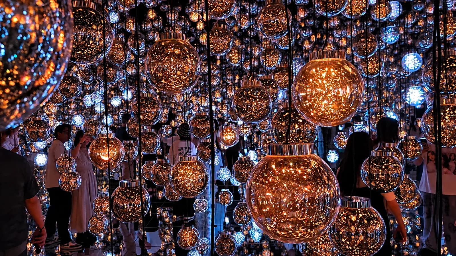 Visitantes entre esferas de luz de colores en el teamLab Borderless