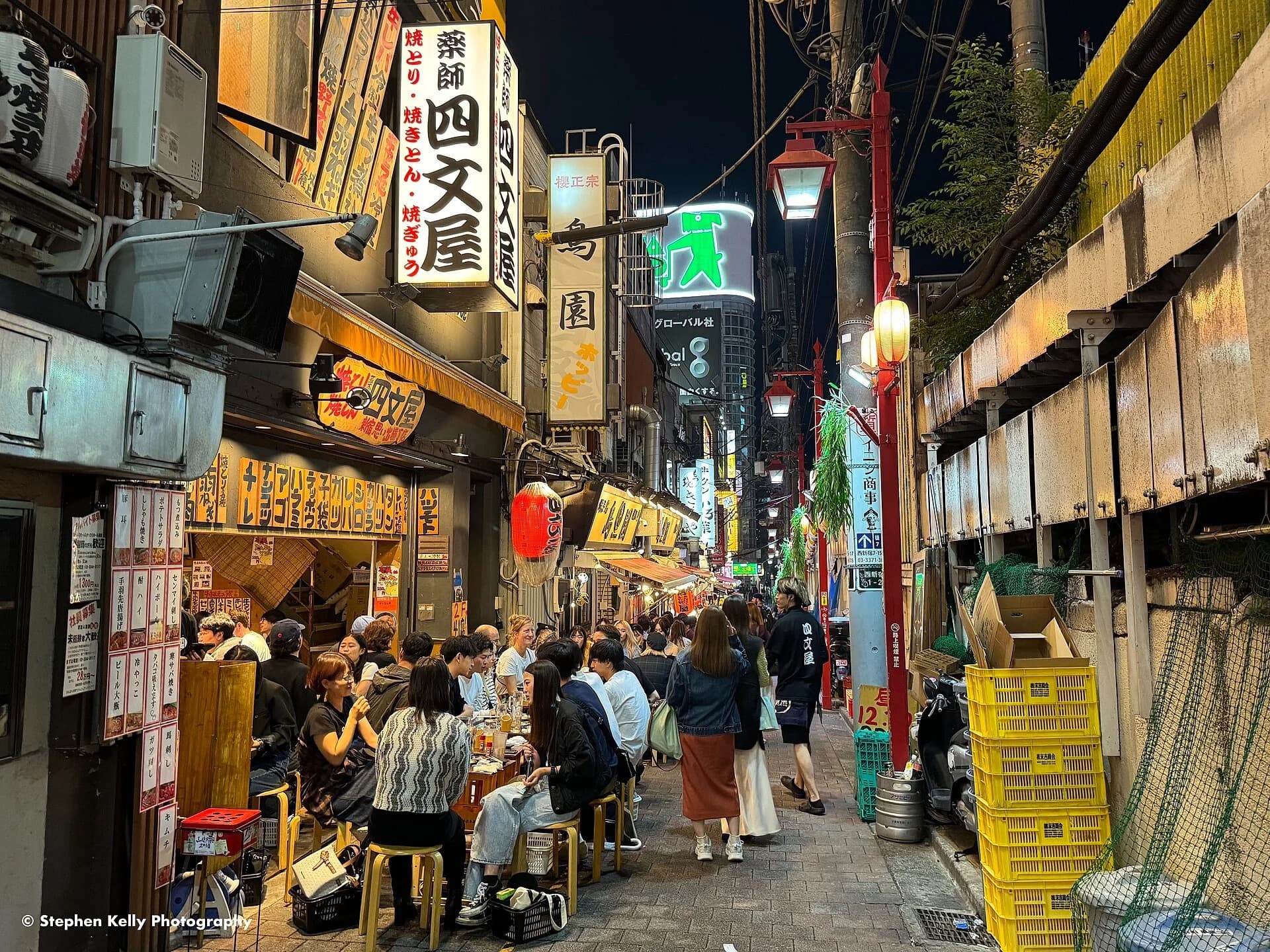 Diners eating at outdoor izakaya tables in Omoide Yokocho, Tokyo