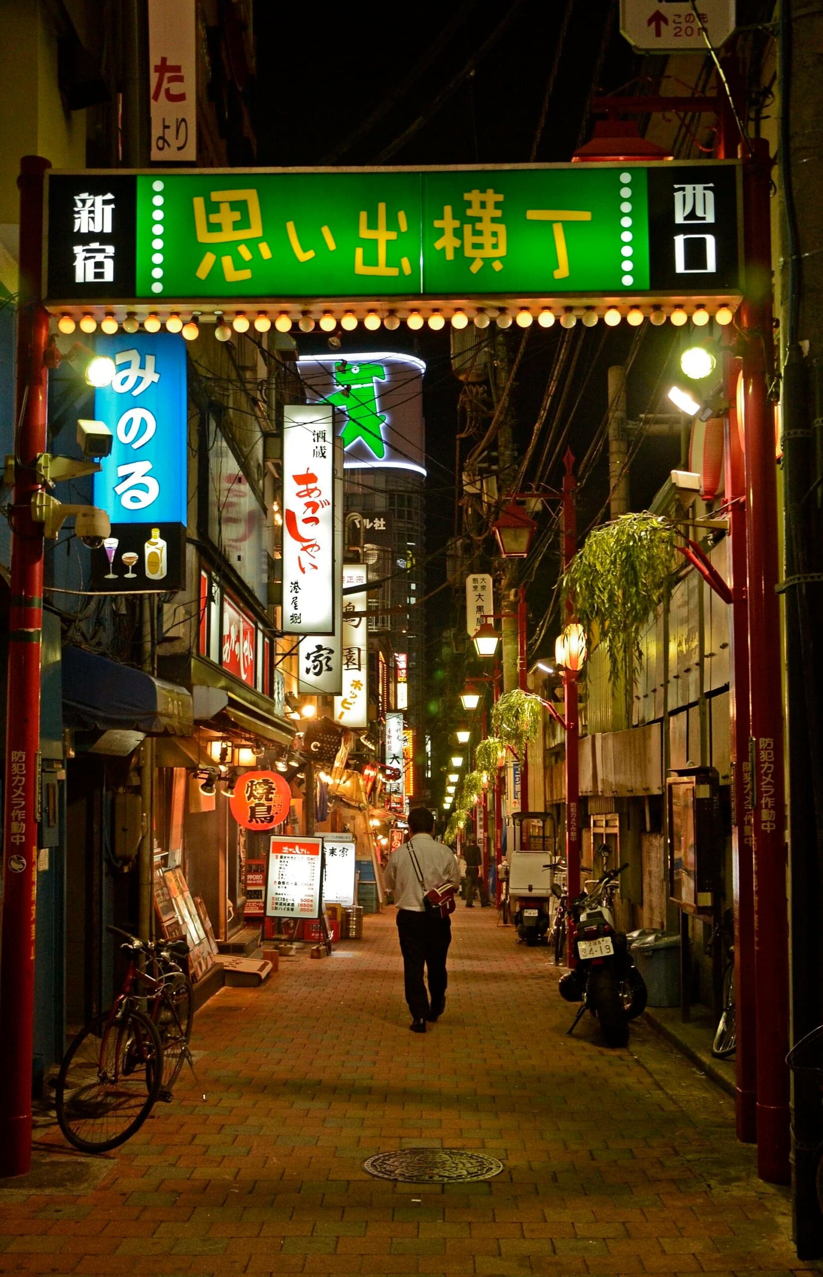 Illuminated entrance to a narrow alley lined with izakayas and restaurants in Shinjuku, Tokyo